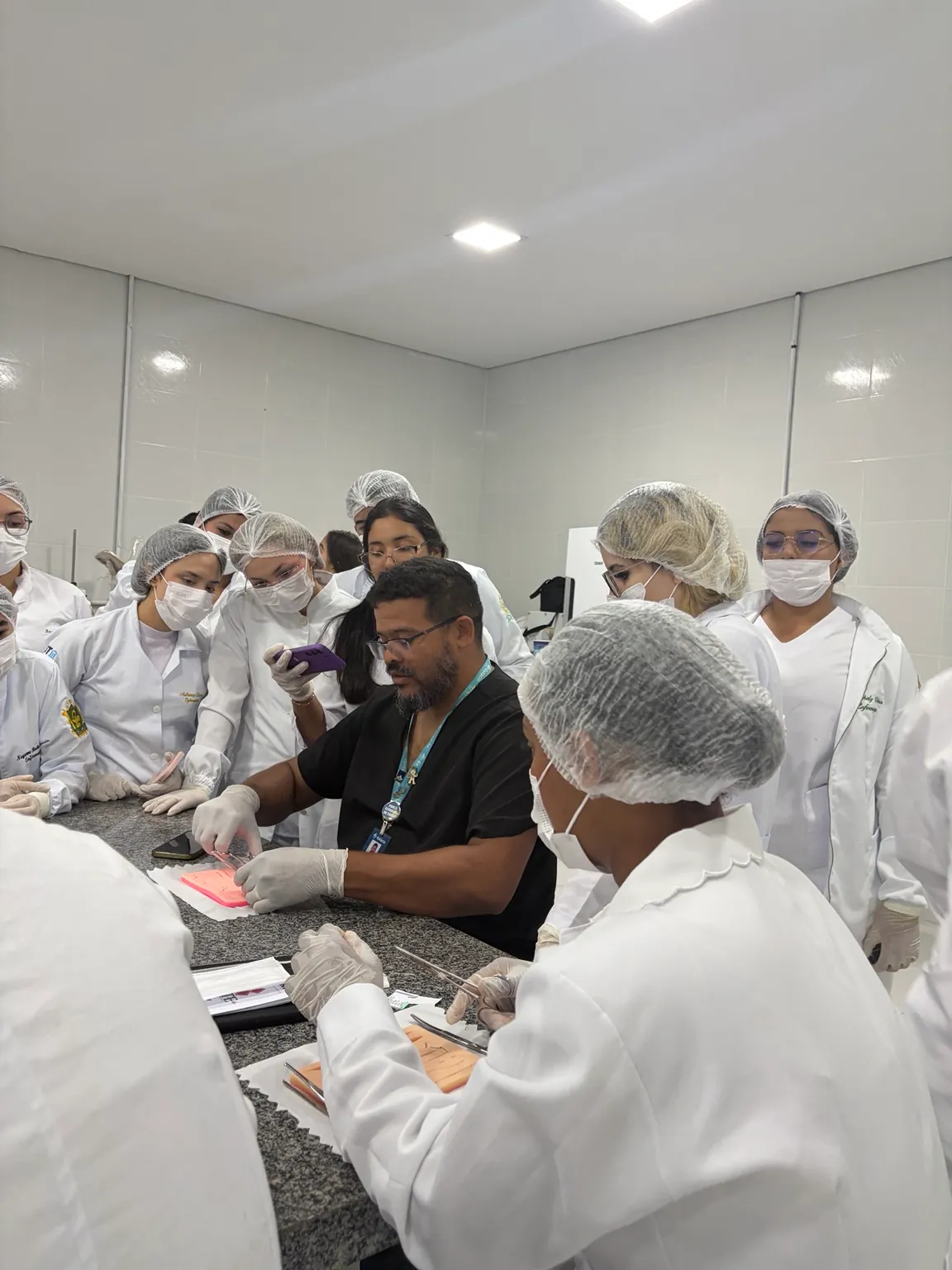 Participantes acompanham de perto uma demonstração de sutura durante atividade da LAUTE.